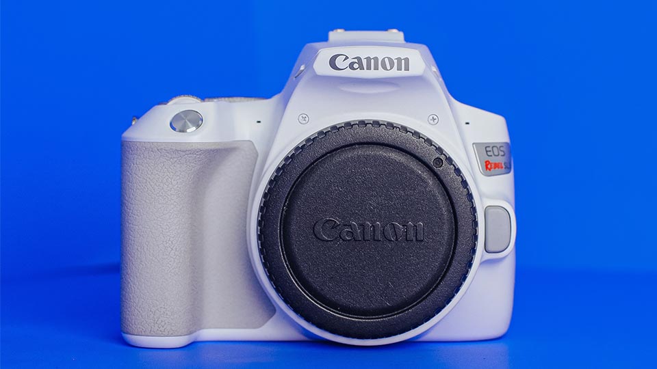 Foto de uma camera DSLR Canon Rebel branca com fundo azul